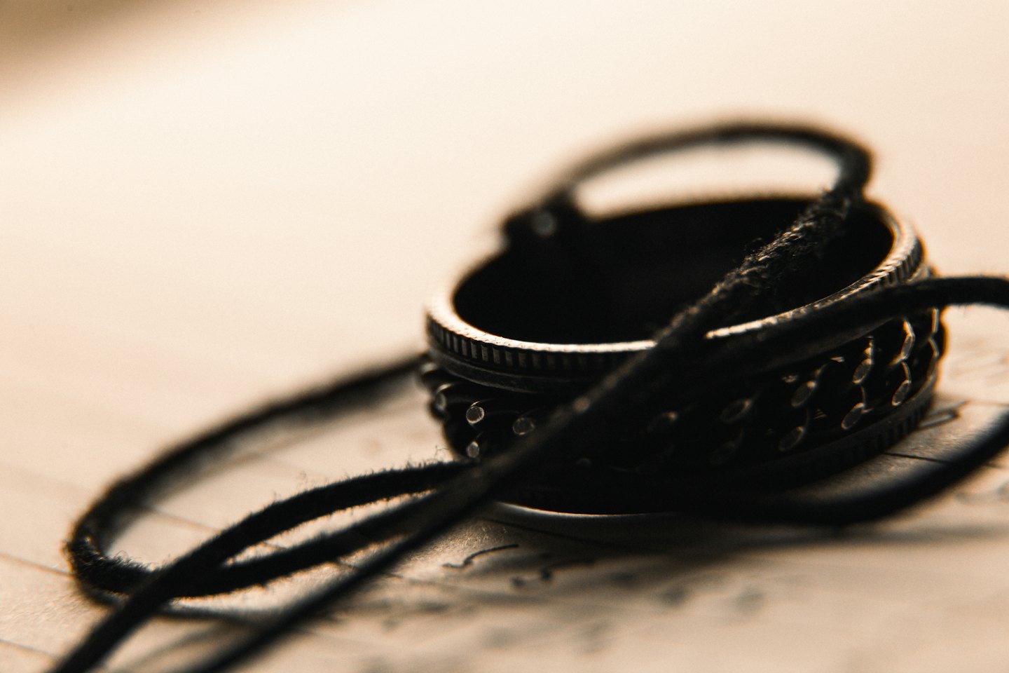 Metal ring with circular studs wrapped in black cord.