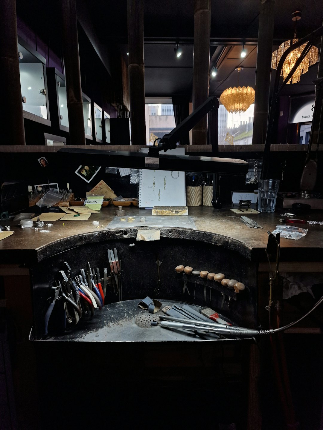 Specialized jeweler tools and design sketches on a wooden workbench.