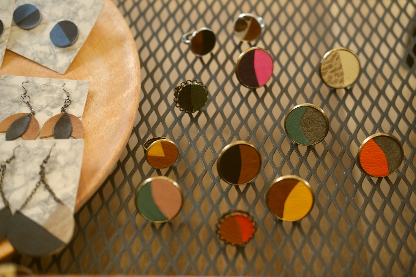 Handcrafted leather rings and earrings on a marble display.