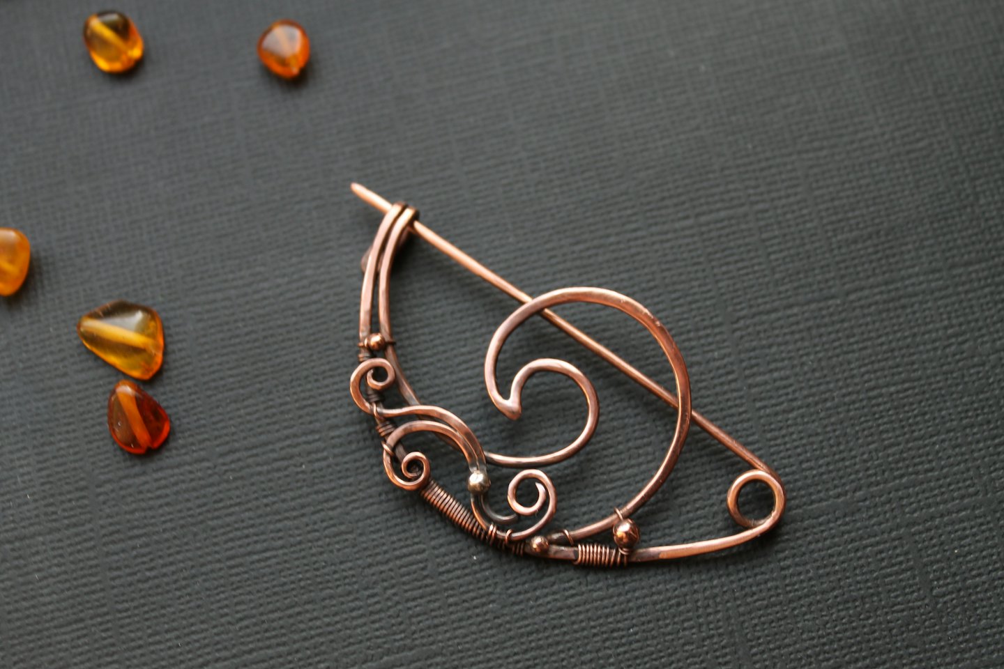 Handcrafted copper wire brooch with scattered amber stones.