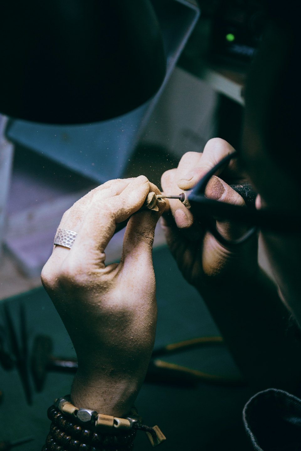 Hands shaping metal with a rotary tool.